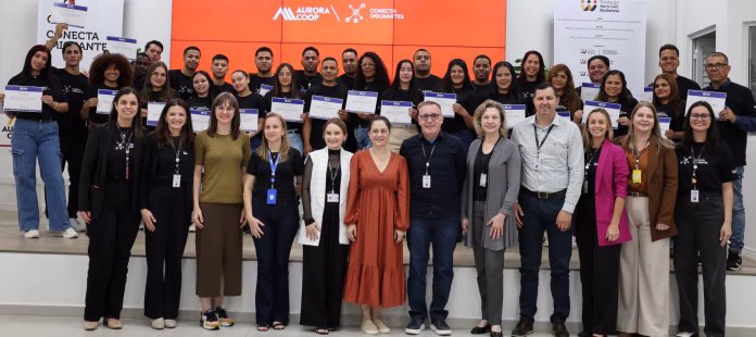 Cerimônia de conclusão do curso Conecta Imigrantes na Aurora Coop com imigrantes formados.