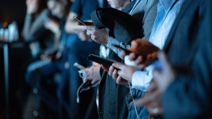 Pessoa olhando celular durante o período eleitoral, com mensagens e redes sociais abertas